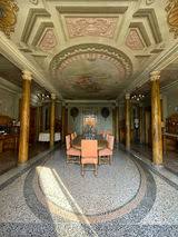Salone interno di Villa Fontedamo: soffitto a cassettoni affrescato, colonne dorate e pavimento a seminato con un grande motivo circolare.